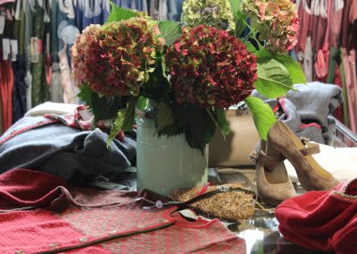 Blumen mit Schuhen und Kleidern auf dem Tisch Huber Mode und Tracht